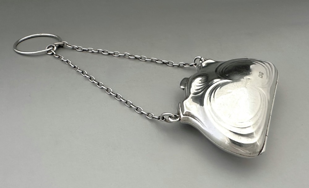 A George V sterling silver cocktail purse with a chain handle, finger ring, and British hallmarks stamped on the contoured front surface. View IV