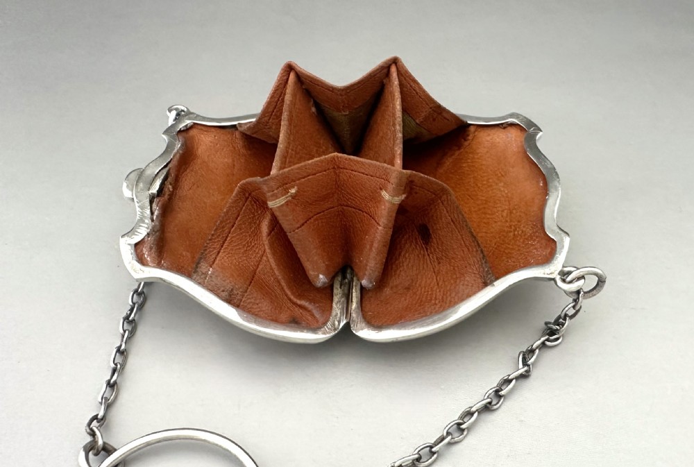 A George V sterling silver cocktail purse with a chain handle, finger ring, and British hallmarks stamped on the contoured front surface. View VIII