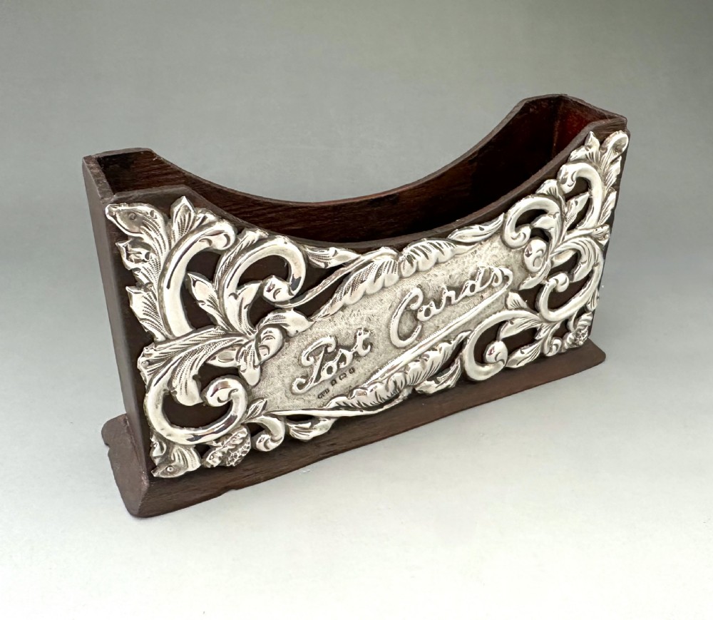 An Edwardian wooden postcard holder featuring an intricate repousse silver mount embossed with the words Post Cards. View II