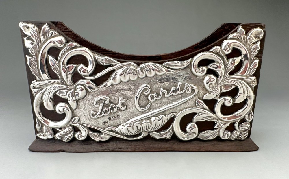 An Edwardian wooden postcard holder featuring an intricate repousse silver mount embossed with the words Post Cards. View III