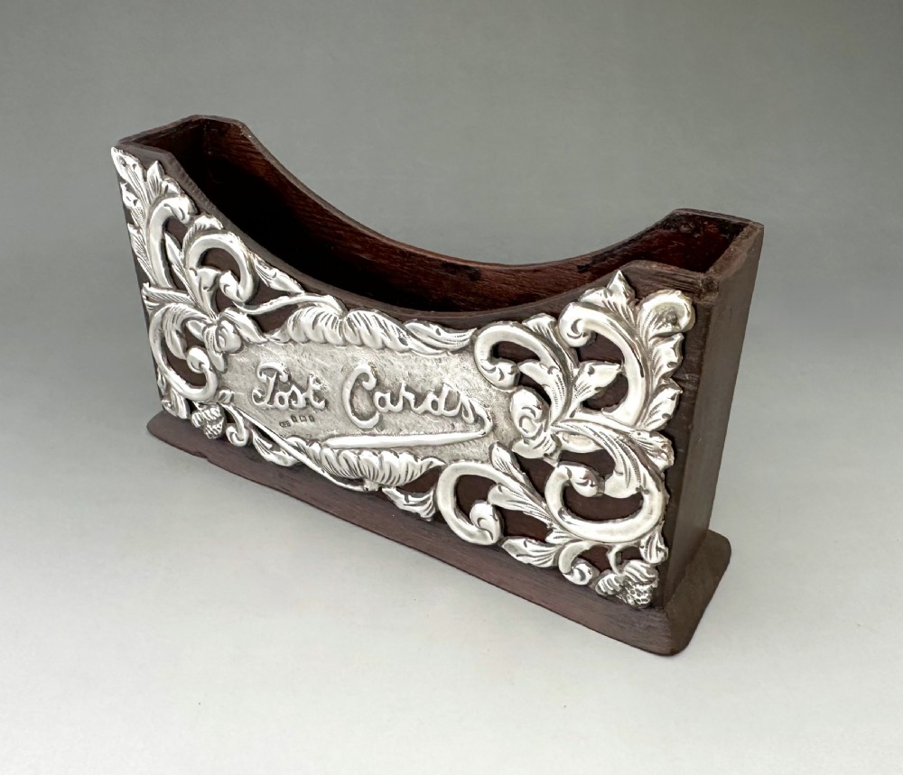 An Edwardian wooden postcard holder featuring an intricate repousse silver mount embossed with the words Post Cards. View IV