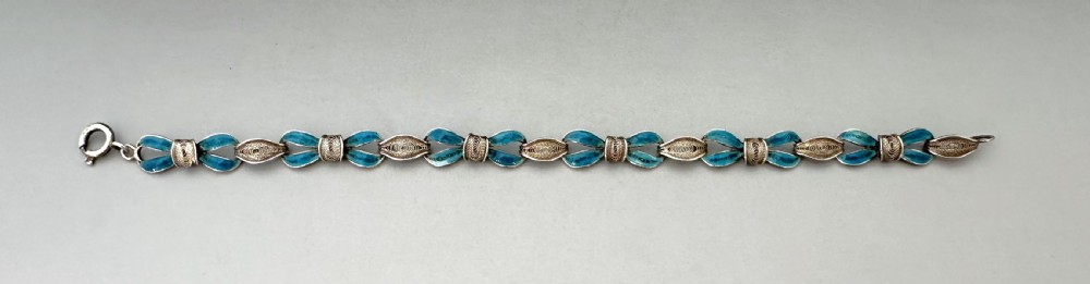 A silver filigree link bracelet featuring bow-shaped segments filled with turquoise blue enamel and secured with a bolt ring clasp. View II