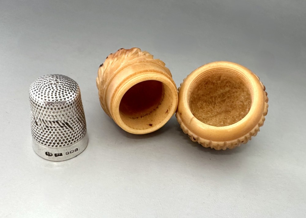 Carved cream and light brown Corozo nut thimble case shaped like an acorn with detailed fluted relief work. View V