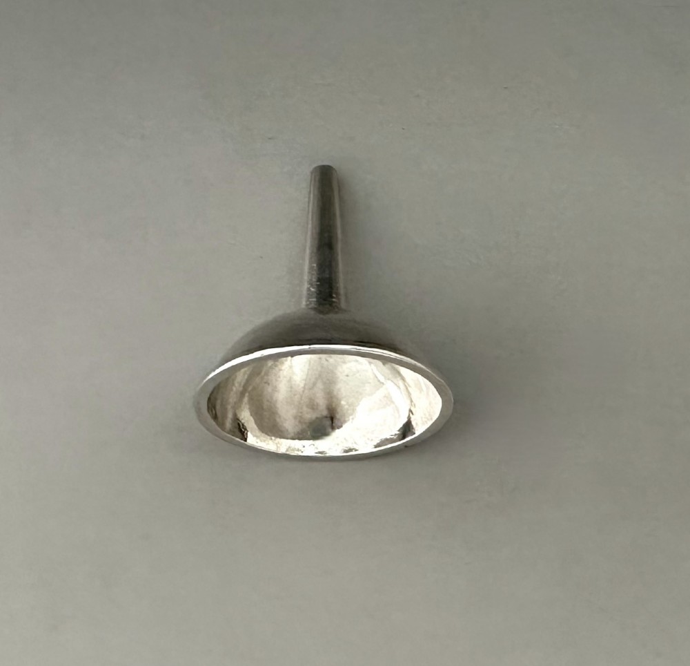 An Old Sheffield plate silver perfume funnel featuring a conical bowl and a narrow tapered spout resting upright. View IV