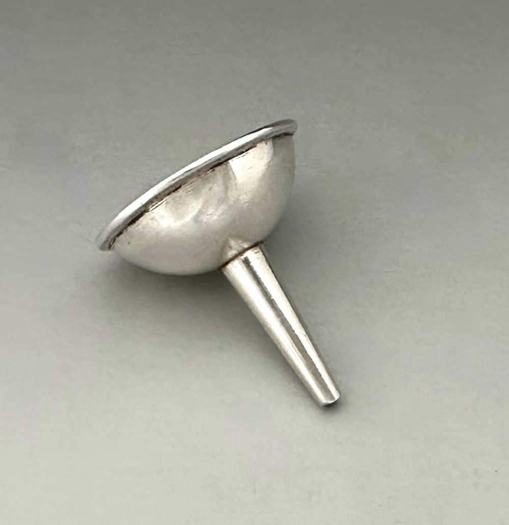 An Old Sheffield plate silver perfume funnel featuring a conical bowl and a narrow tapered spout resting upright. View V