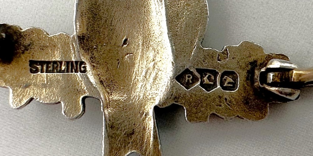 A silver-gilt brooch depicting two light blue enamel birds perched on a flowering branch with white enamel blossoms. View V