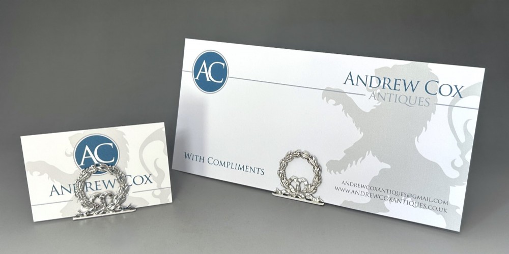 A pair of sterling silver menu card holders shaped as laurel and oak leaf wreaths tied with a ribbon bow on a flat base with rear support struts. View VII
