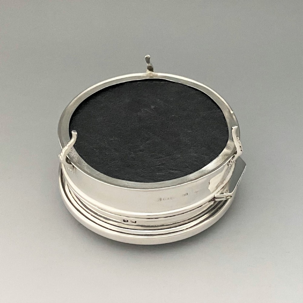 A circular sterling silver trinket box resting on four cabriole legs featuring a dark tortoiseshell lid inlaid with a silver floral garland motif. View VII
