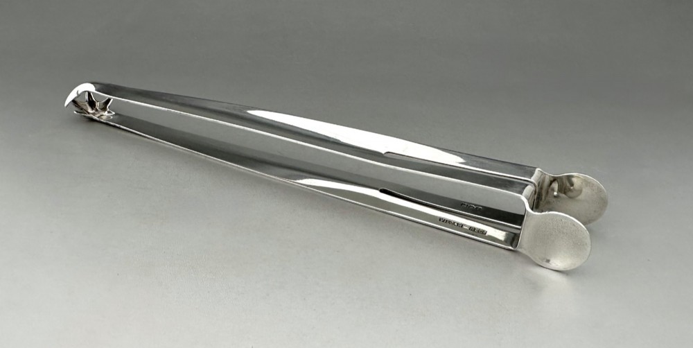 A pair of polished silver Edwardian bar tongs featuring slender arms with mechanical claw gripping ends and flat finger pads. View II