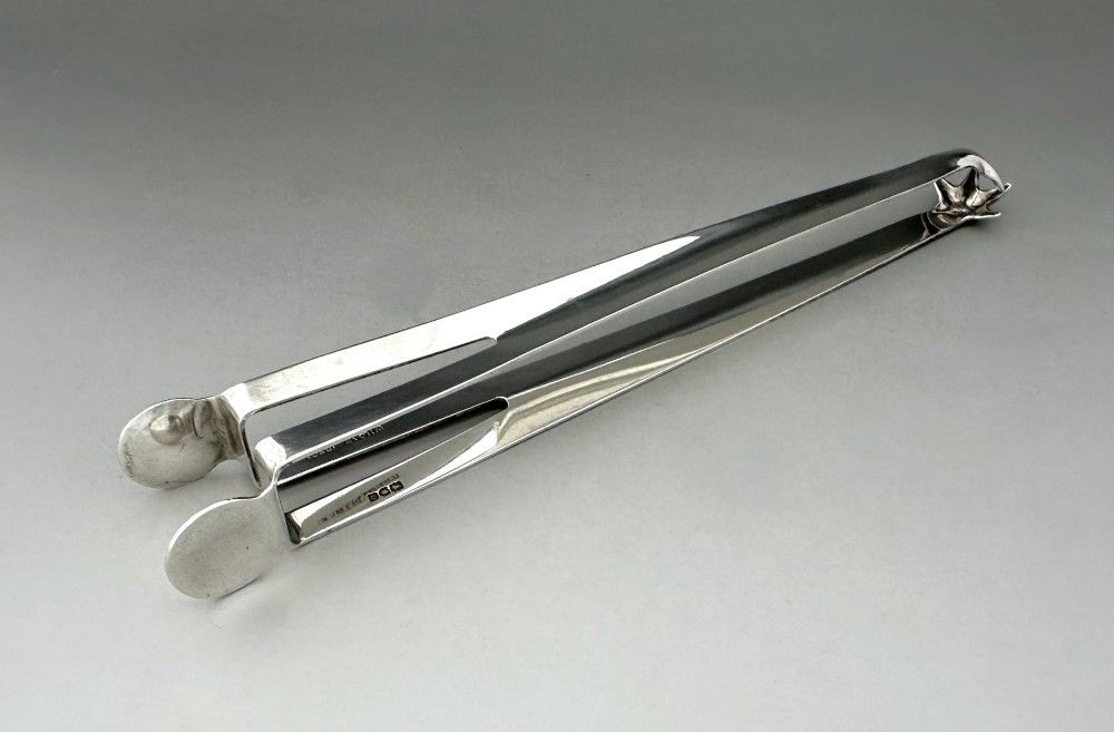A pair of polished silver Edwardian bar tongs featuring slender arms with mechanical claw gripping ends and flat finger pads. View III