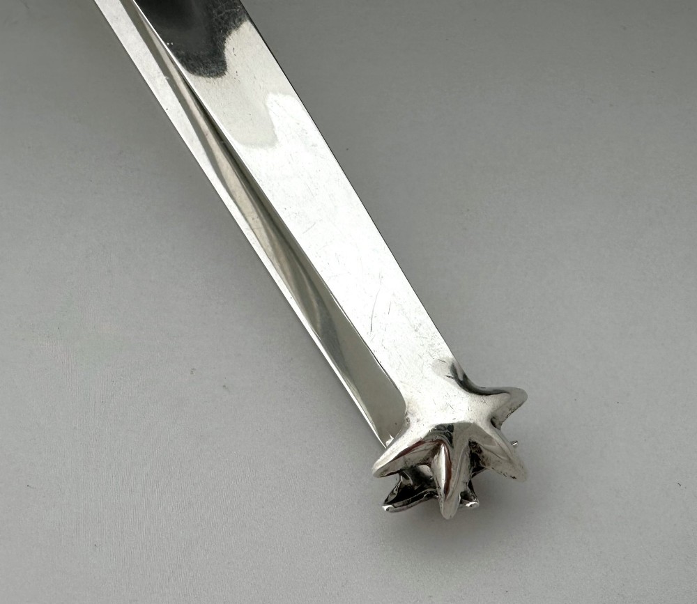 A pair of polished silver Edwardian bar tongs featuring slender arms with mechanical claw gripping ends and flat finger pads. View V