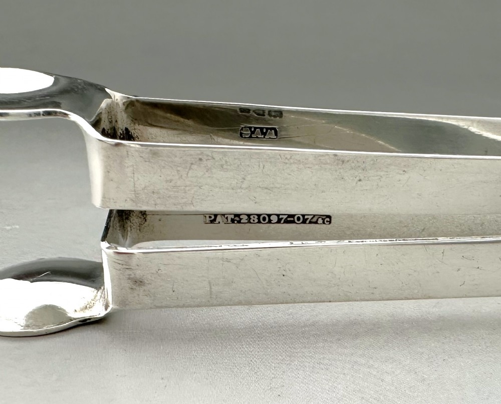A pair of polished silver Edwardian bar tongs featuring slender arms with mechanical claw gripping ends and flat finger pads. View VIII