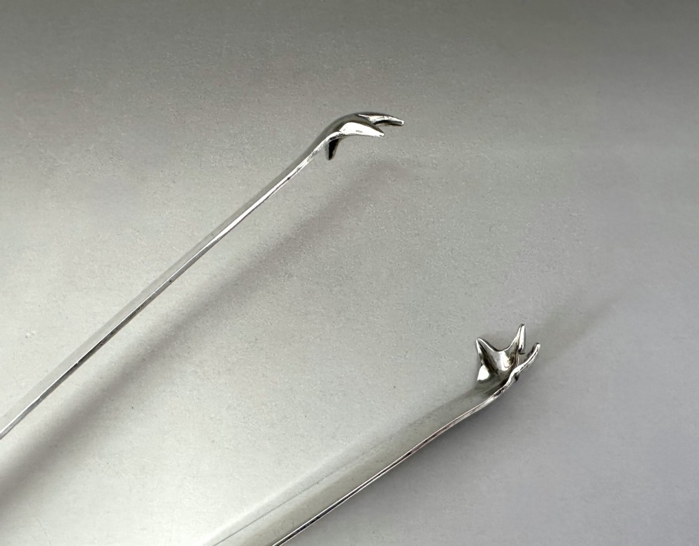 A pair of polished silver Edwardian bar tongs featuring slender arms with mechanical claw gripping ends and flat finger pads. View IX