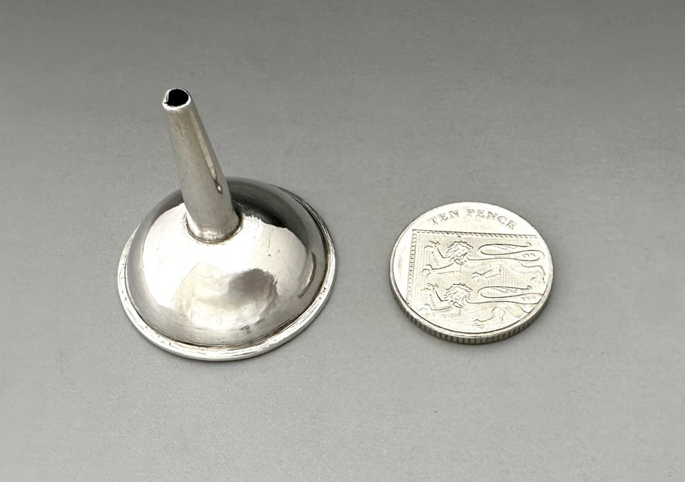 An Old Sheffield plate silver perfume funnel featuring a conical bowl and a narrow tapered spout resting upright. View VII