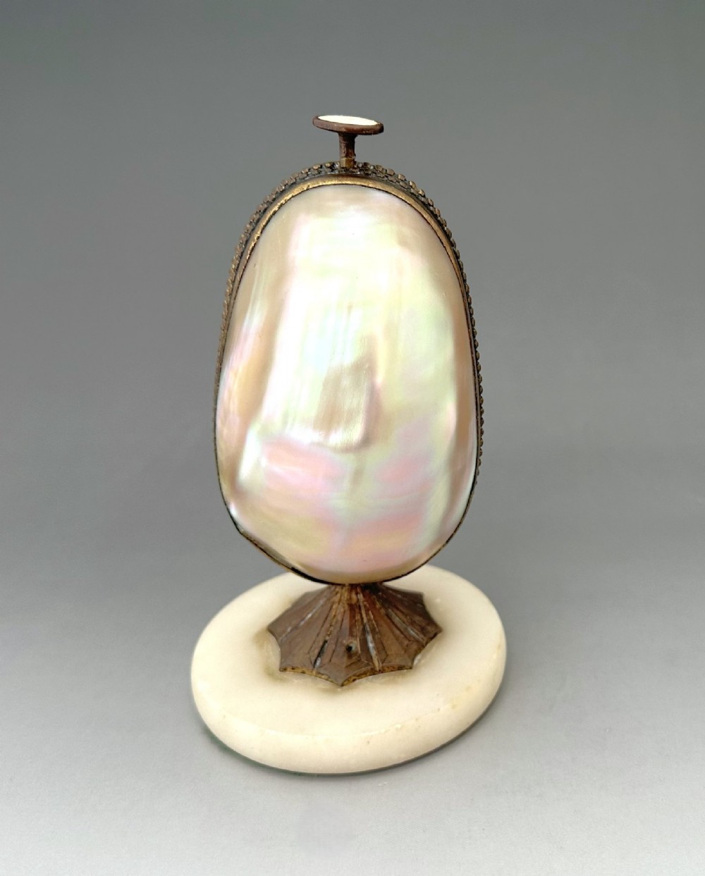 An open French Palais Royal mother-of-pearl egg-shaped etui featuring gilt bronze trim, a green velvet central cushion, and a round alabaster base. View III