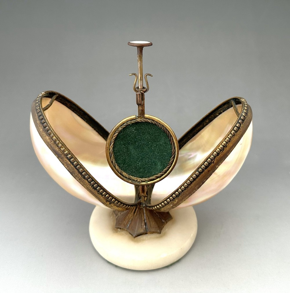 An open French Palais Royal mother-of-pearl egg-shaped etui featuring gilt bronze trim, a green velvet central cushion, and a round alabaster base.