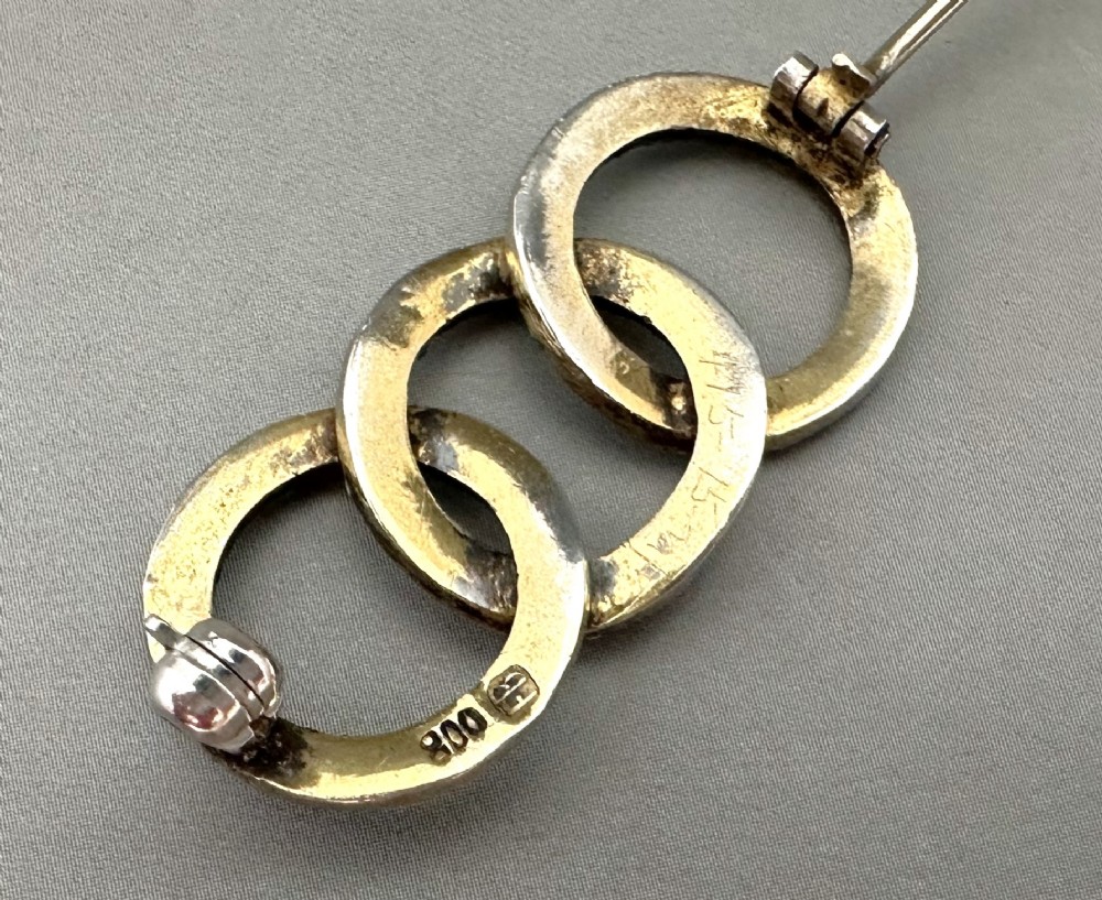 A silver gilt horizontal brooch formed of three interlocking circular rings set with turquoise cabochons and split seed pearls. View IV