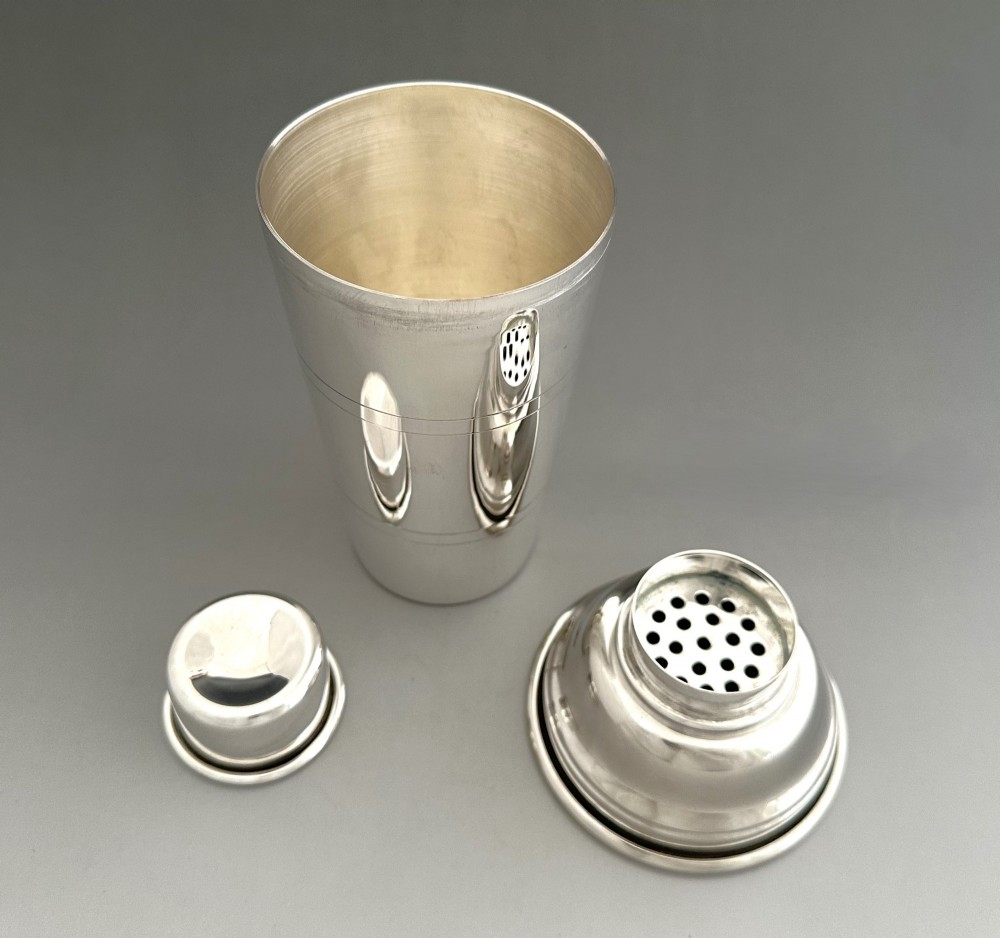 A polished silver-plated three-piece Art Deco cocktail shaker featuring a tapered cylindrical body with incised lines and a stepped cap. View III