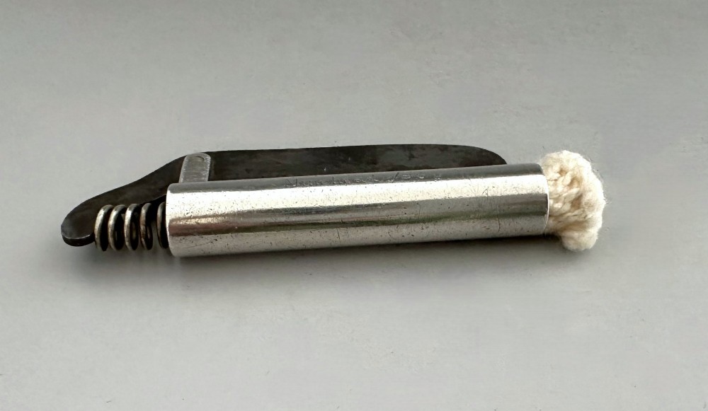 An antique Victorian silver tinder tube with engraved maker details, a steel striker plate, and a protruding cotton wick. View II
