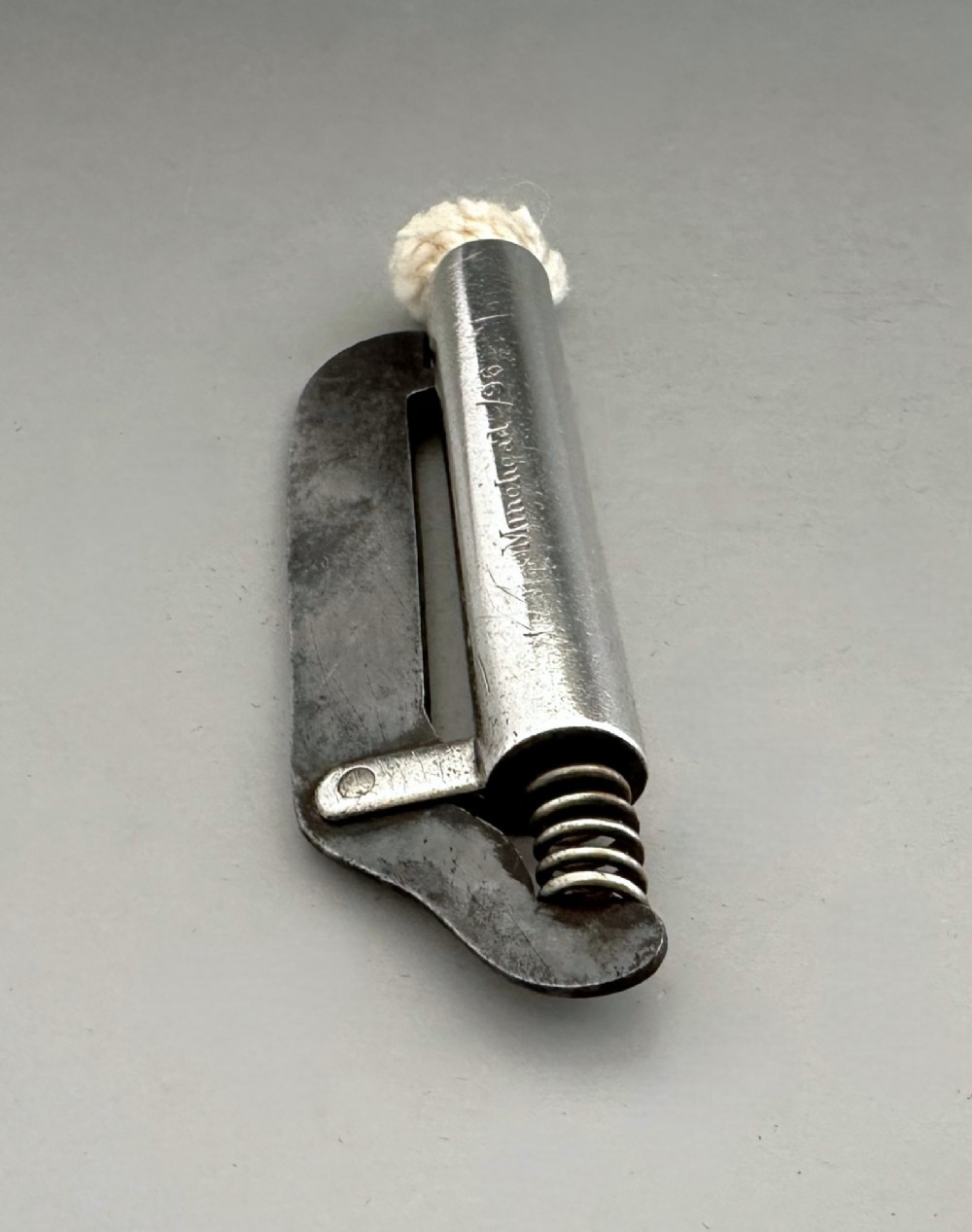 An antique Victorian silver tinder tube with engraved maker details, a steel striker plate, and a protruding cotton wick. View III