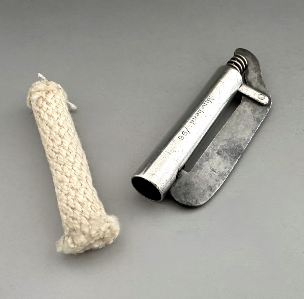 An antique Victorian silver tinder tube with engraved maker details, a steel striker plate, and a protruding cotton wick. View V