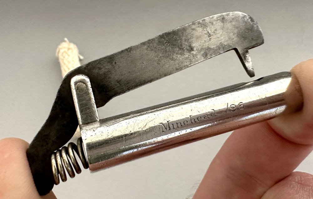 An antique Victorian silver tinder tube with engraved maker details, a steel striker plate, and a protruding cotton wick. View VI