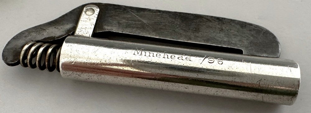 An antique Victorian silver tinder tube with engraved maker details, a steel striker plate, and a protruding cotton wick. View VII