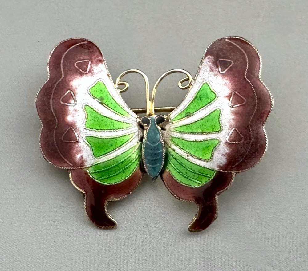 An antique butterfly brooch constructed from silver gilt and detailed with green, white, and burgundy enamel on the wings. View II