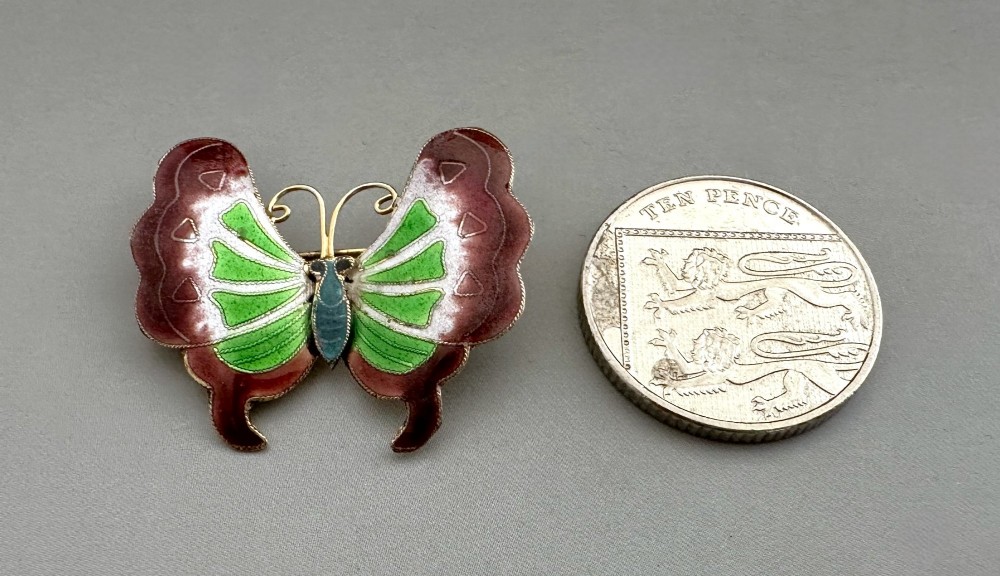 An antique butterfly brooch constructed from silver gilt and detailed with green, white, and burgundy enamel on the wings. View VI