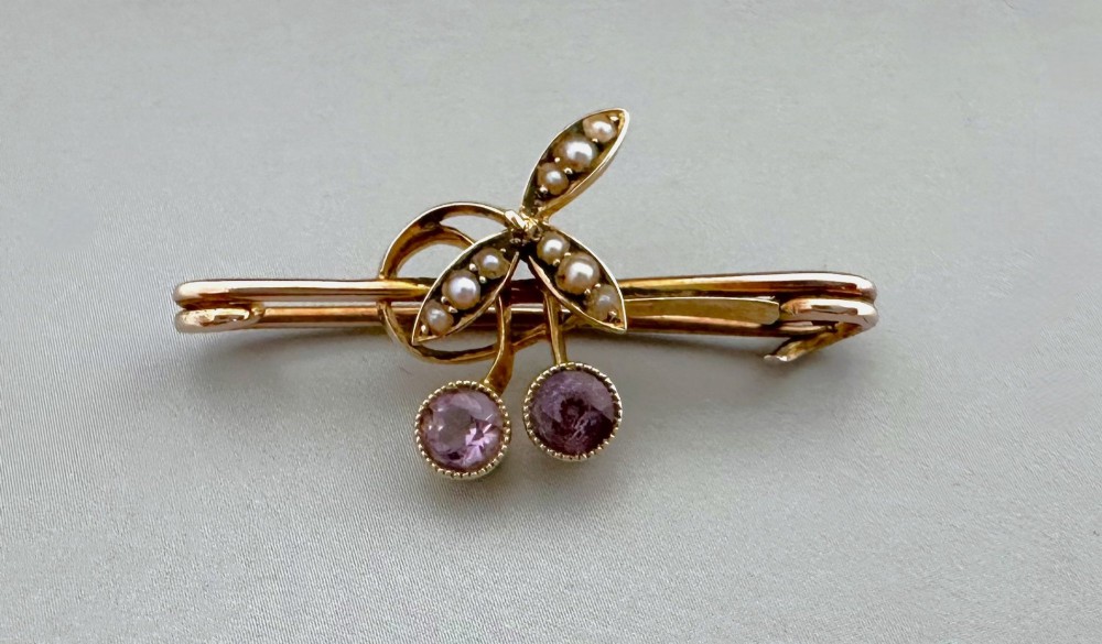 Victorian 9ct gold bar brooch featuring a central cherry motif with seed pearl leaves and two faceted pink gemstones.
