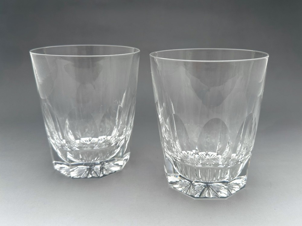 A pair of clear cut glass whisky tumblers featuring arched facet cuts and starburst bases.