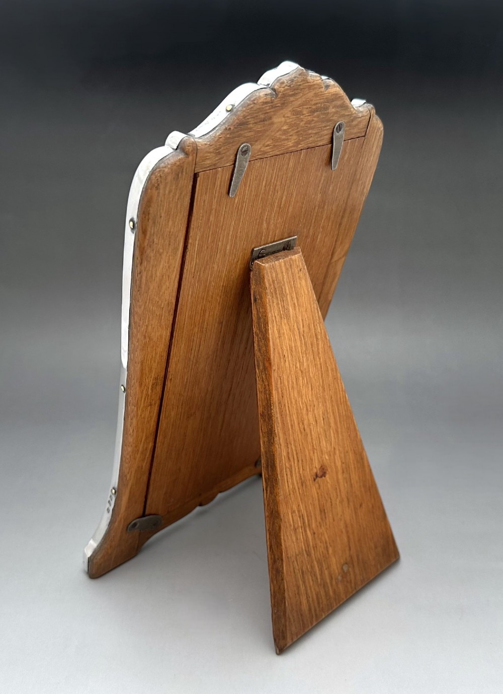 A George V polished silver picture frame with a shaped arched top and a dark wooden easel backing. View III