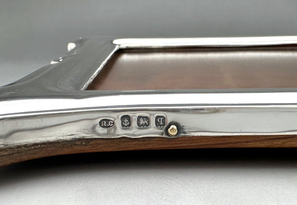 A George V polished silver picture frame with a shaped arched top and a dark wooden easel backing. View VII