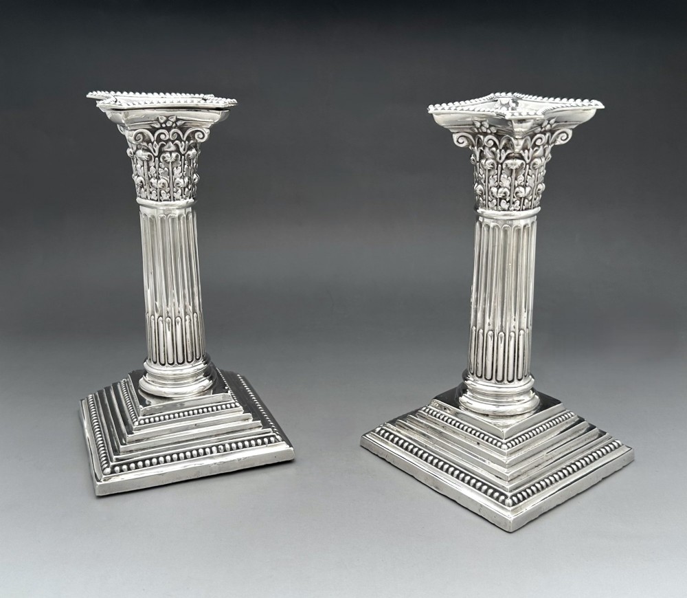 A pair of Victorian silver candlesticks featuring fluted Corinthian columns with acanthus leaf capitals on stepped square bases with beaded rims. View II