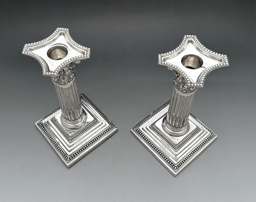 A pair of Victorian silver candlesticks featuring fluted Corinthian columns with acanthus leaf capitals on stepped square bases with beaded rims. View III