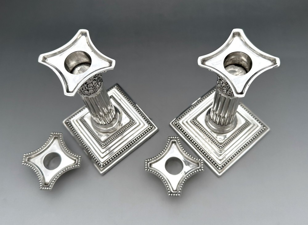 A pair of Victorian silver candlesticks featuring fluted Corinthian columns with acanthus leaf capitals on stepped square bases with beaded rims. View IV