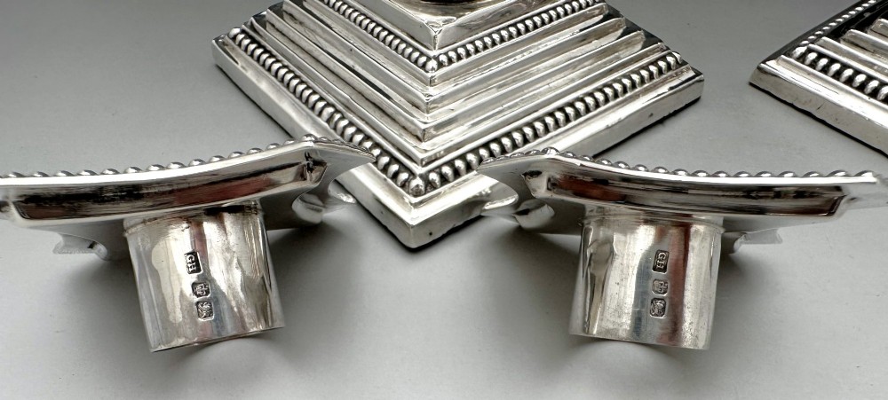 A pair of Victorian silver candlesticks featuring fluted Corinthian columns with acanthus leaf capitals on stepped square bases with beaded rims. View V