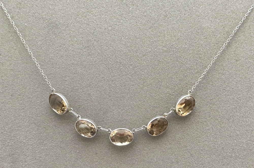 An early twentieth-century fine silver chain necklace set with five oval faceted citrine gemstones in bezel mountings.