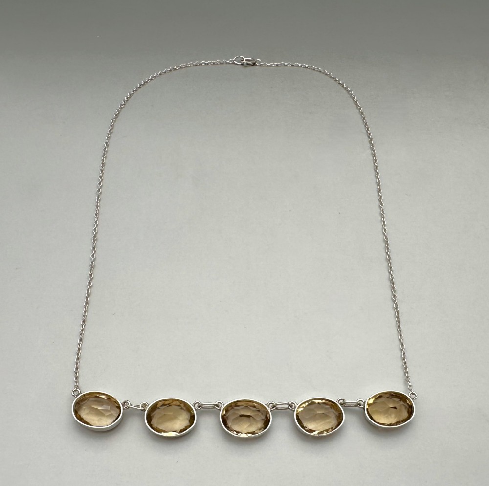 An early twentieth-century fine silver chain necklace set with five oval faceted citrine gemstones in bezel mountings. View V