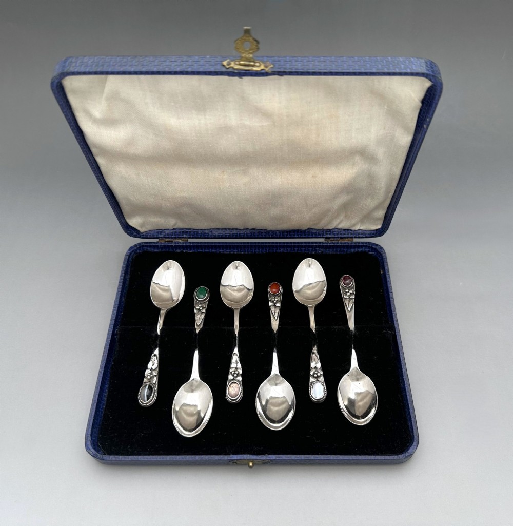 A boxed set of six Scottish sterling silver demi-tasse spoons set with varied semi-precious cabochon stones in a blue fitted case.
