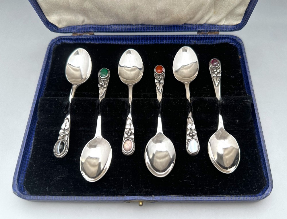 A boxed set of six Scottish sterling silver demi-tasse spoons set with varied semi-precious cabochon stones in a blue fitted case. View II