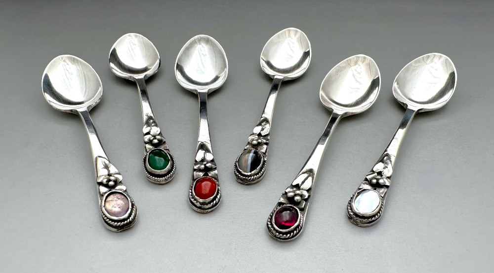 A boxed set of six Scottish sterling silver demi-tasse spoons set with varied semi-precious cabochon stones in a blue fitted case. View V