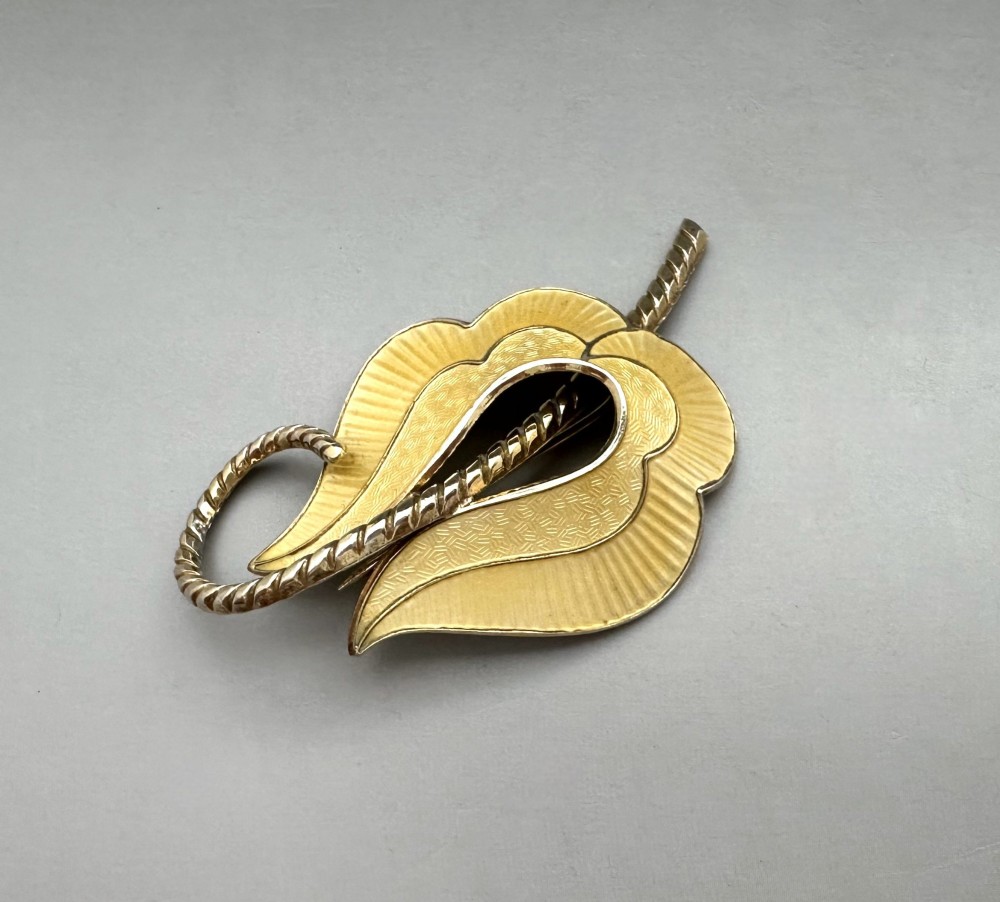 A leaf-shaped Norwegian silver gilt brooch featuring layered yellow guilloche enamel and twisted silver accents.