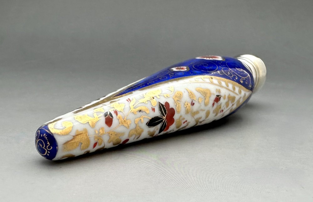 A Victorian teardrop-shaped porcelain scent bottle decorated with blue, red, and gold Imari motifs, featuring a silver spherical cap. View III