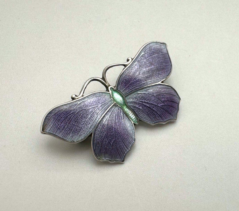 An Edwardian silver butterfly brooch featuring purple textured guilloche enamel wings and a green enamelled body. View II
