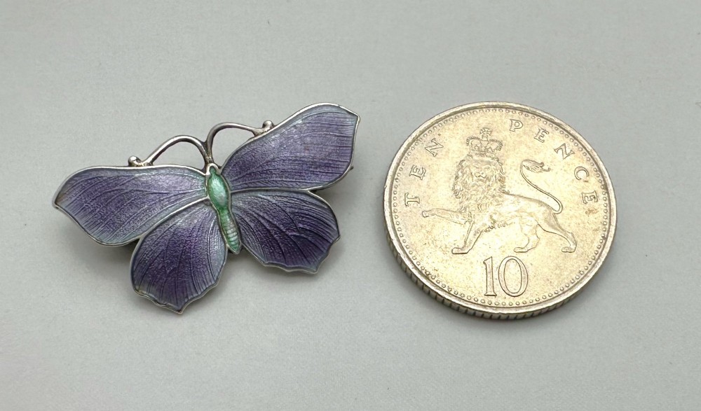 An Edwardian silver butterfly brooch featuring purple textured guilloche enamel wings and a green enamelled body. View IV