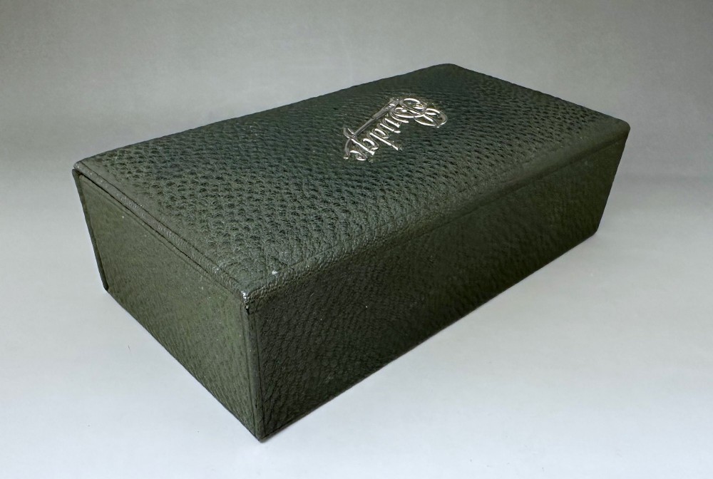 A dark green pebbled leather rectangular bridge box featuring applied silver script spelling Bridge on the top cover and a silver clasp closure. View III