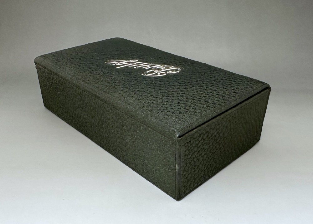 A dark green pebbled leather rectangular bridge box featuring applied silver script spelling Bridge on the top cover and a silver clasp closure. View IV