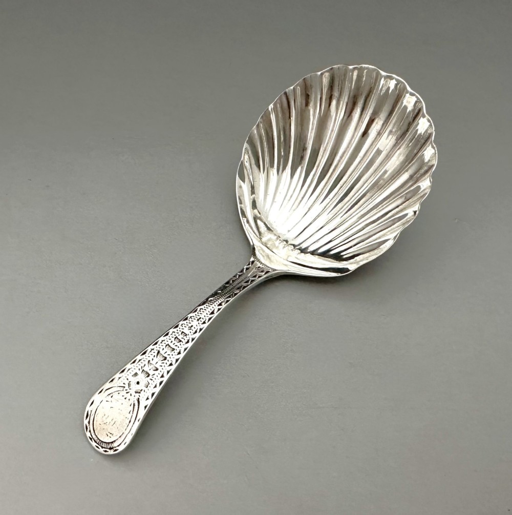 An 18th-century sterling silver caddy spoon featuring a fluted shell-shaped bowl and an intricately engraved handle. View II