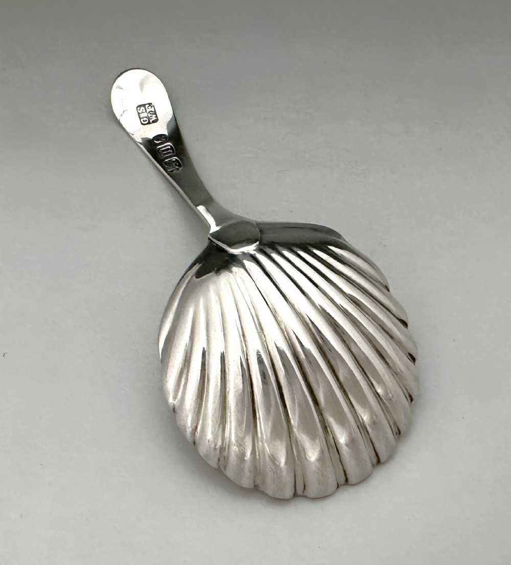 An 18th-century sterling silver caddy spoon featuring a fluted shell-shaped bowl and an intricately engraved handle. View IV